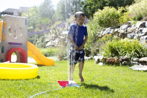 Caucasian boy playing in backyard sprinkler
