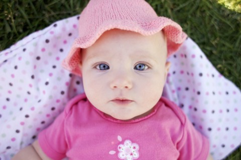 Serious Caucasian baby laying in grass