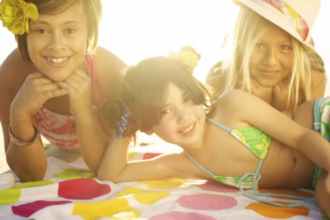 Children in bikinis laying on towel