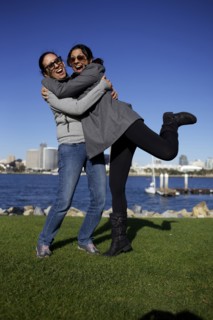 Grinning mixed race sisters hugging outdoors