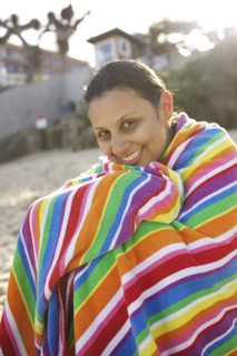 Mixed race woman sitting on beach wrapped in towel