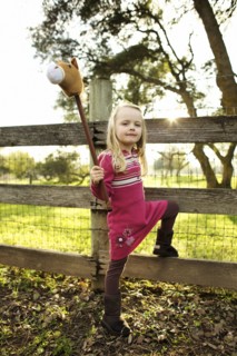 Caucasian girl holding stick horse near fence