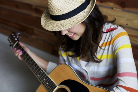 Mixed race woman playing guitar