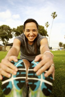 Hispanic woman stretching in park before exercising