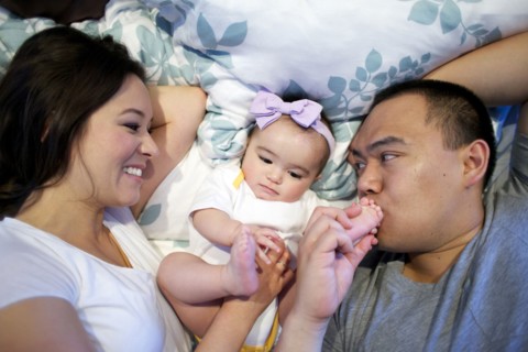 Mother and father laying in bed with baby girl