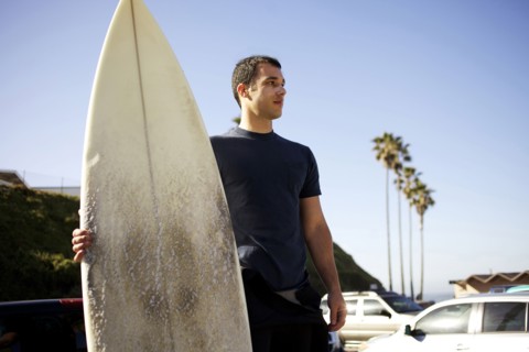 Man holding surfboard in parking lot