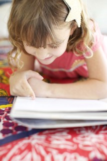 Mixed race girl reading on bed
