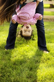 Mother holding toddler daughter upside down