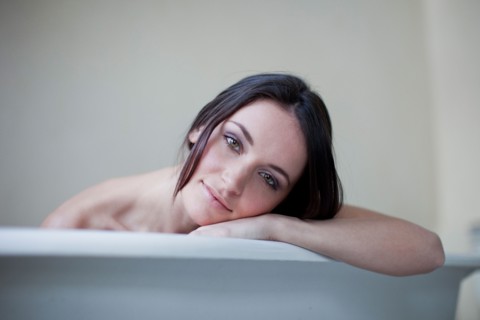 Caucasian woman leaning on side of bathtub