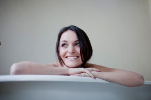 Caucasian woman leaning on side of bathtub