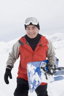 Senior Hispanic man snowboarding