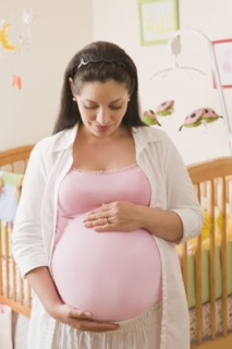 Pregnant Hispanic woman standing in nursery