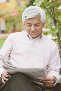 Senior Hispanic man reading newspaper