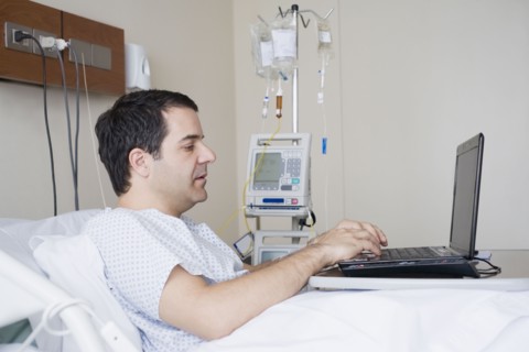 Hispanic man using laptop in hospital