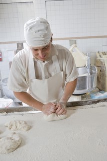 Hispanic baker kneading dough