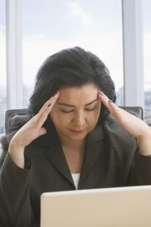 Hispanic businesswoman with headache using laptop
