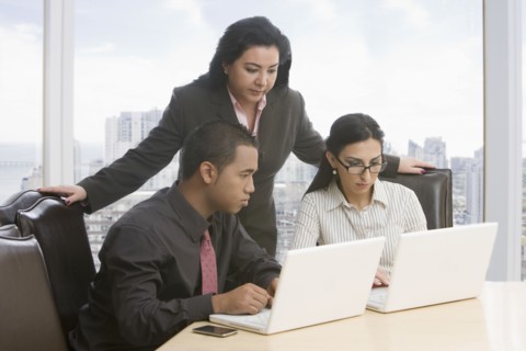 Business people in meeting using laptops