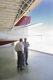 Hispanic businessmen standing in airplane hangar