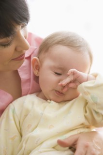 Hispanic mother watching baby rubbing her nose