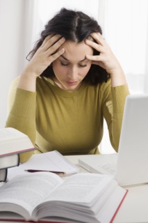 Mixed race woman with headache studying textbooks