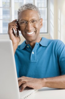 Mixed race man with laptop talking on cell phone