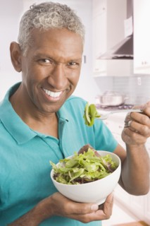 Mixed race man eating salad in kitchen