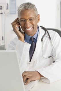 Mixed race doctor sitting at desk talking on cell phone