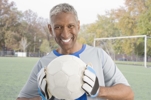 Mixed race man in soccer uniform holding ball