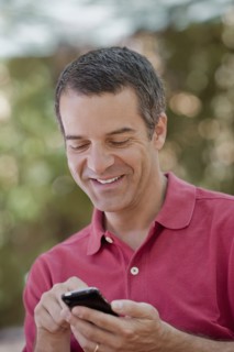 Hispanic man text messaging on cell phone