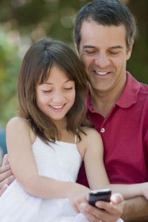 Hispanic father and daughter text messaging on cell phone