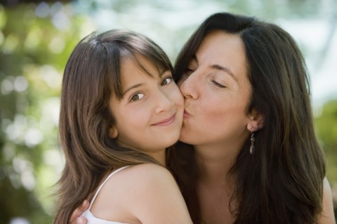 Hispanic mother kissing daughter