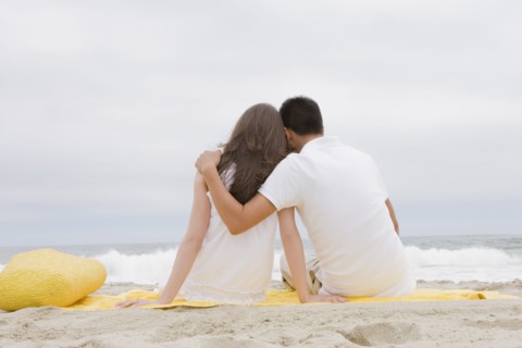 Hispanic couple sitting on beach together