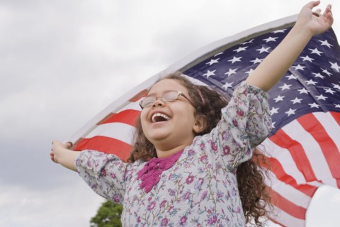 Hispanic girl holding American flag with arms raised