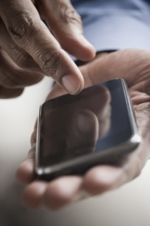 Mixed race man text messaging on cell phone