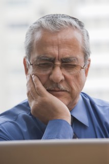Frowning Hispanic businessman using laptop
