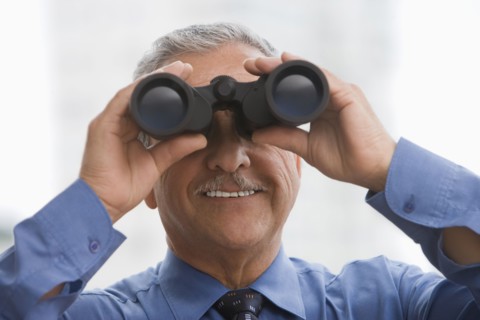 Hispanic businessman using binoculars