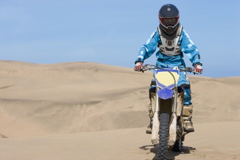 Chilean teenager riding motorcycle on sand dune