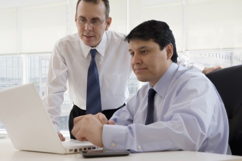 Hispanic businessman looking at laptop together