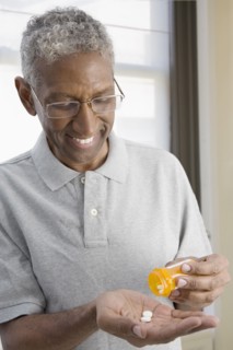 Mixed race man shaking pills from bottle