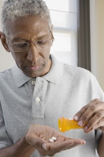 Mixed race man shaking pills from bottle