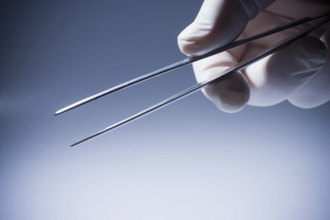 Close up of Hispanic doctor holding tweezers