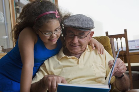 Older Hispanic man reading to granddaughter
