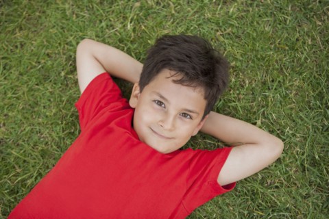 Hispanic boy laying in grass