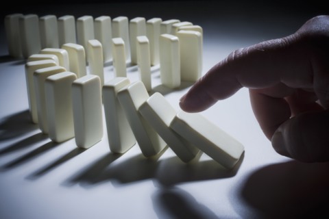 Hispanic man knocking over dominoes