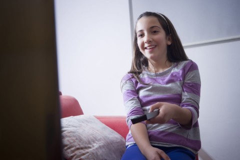 Hispanic girl watching television on sofa