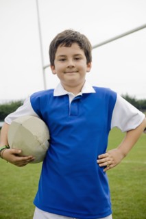 Hispanic boy holding rugby ball on field