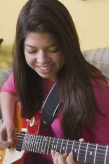Hispanic girl playing guitar on sofa