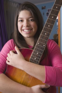 Hispanic girl hugging guitar