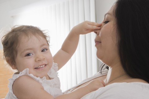 Hispanic baby girl touching mother's nose