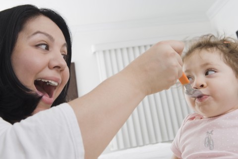 Hispanic mother feeding baby girl